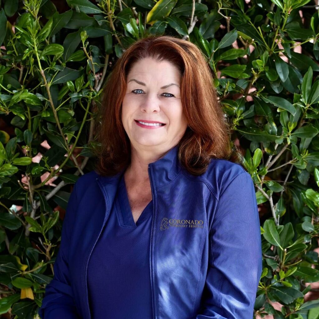 Dr Elizabeth Stone Female veterinarian wearing a purple jacket standing in front of a bush
